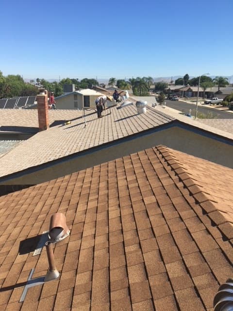 Baker Roofing crew repairing a shingle roof on a sunny Menifee street